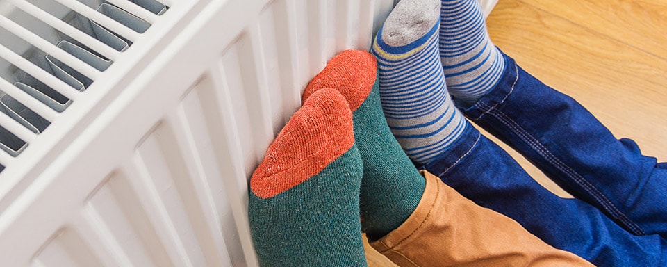 Voeten van een vader en een zoon in gekleurde sokken tegen de verwarming 