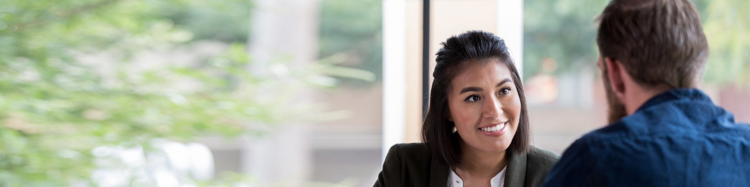 Vrouw en man zittend aan een tafel voeren een gesprek