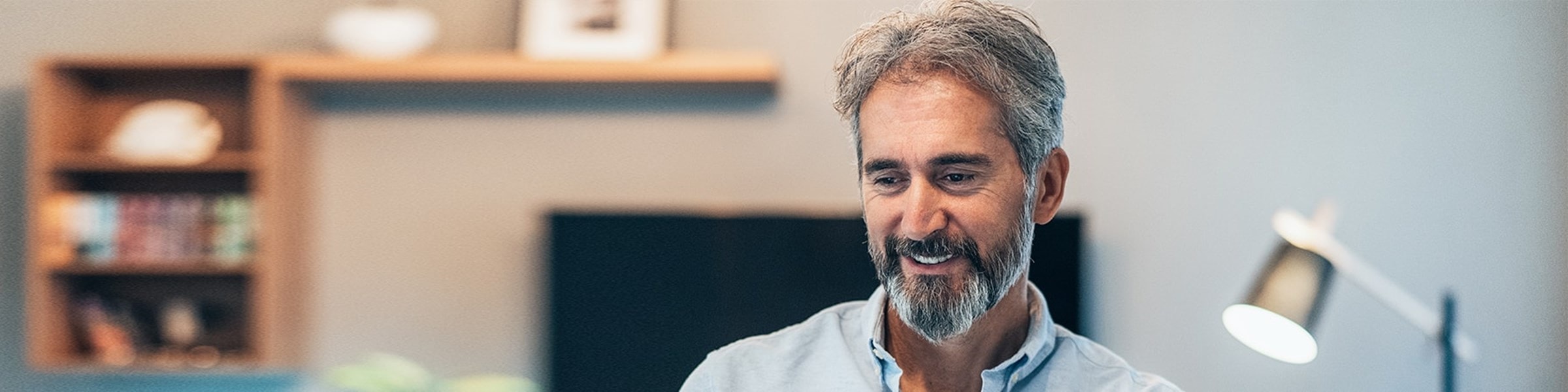 Man glimlacht en zit achter zijn laptop en kijkt op zijn scherm