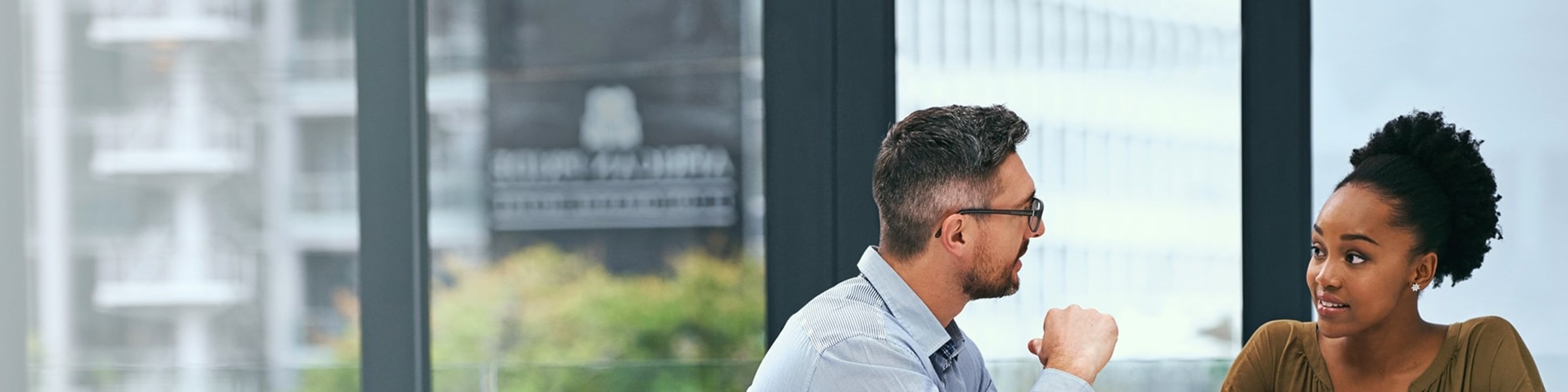 Een man en een vrouw zitten achter een bureau en voeren een serieus gesprek