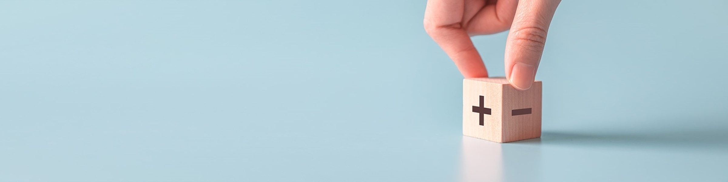 Een houten blokje met een plus en een min erop