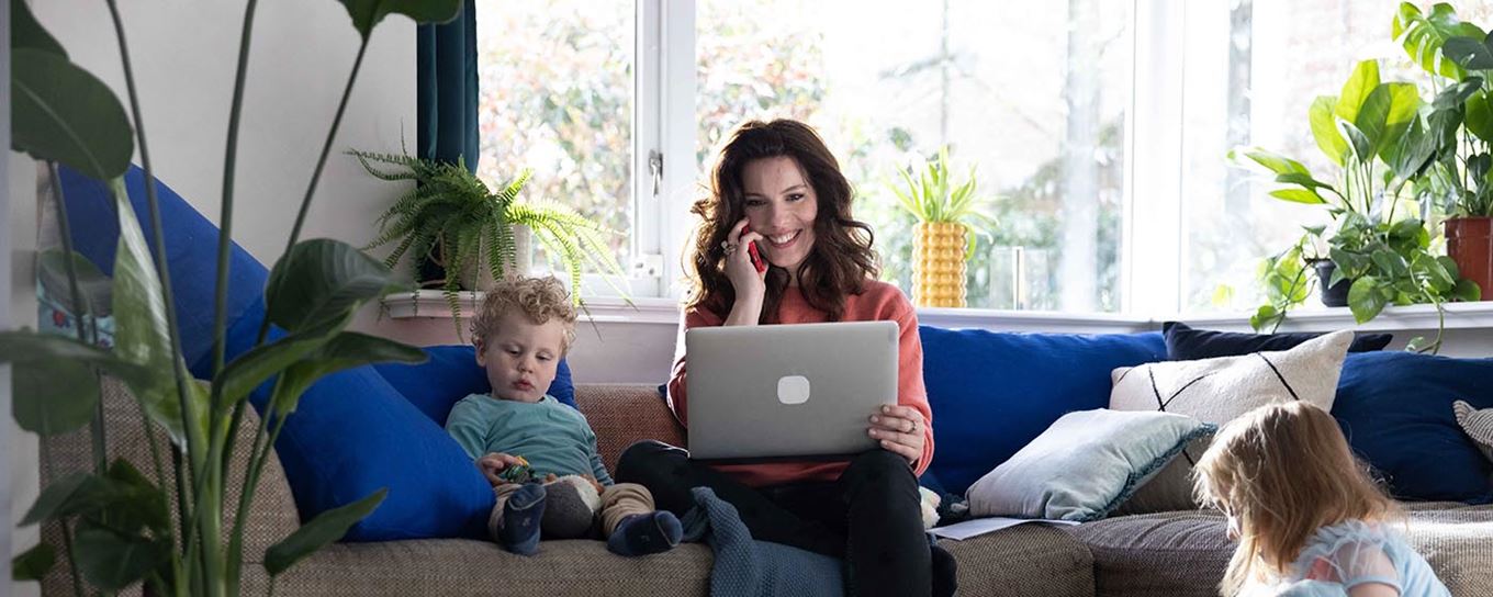 Vrouw met kleine kinderen om haar heen belt en kijkt op laptop | a.s.r.