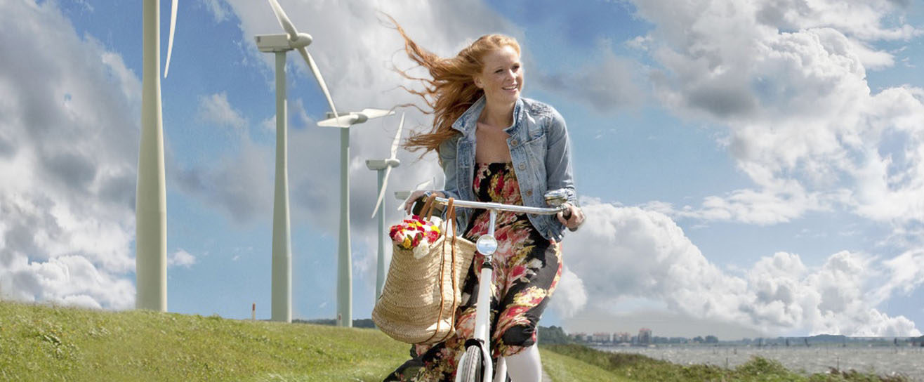 Vrouw fietst langs het water met een rij windmolens op de achtergrond