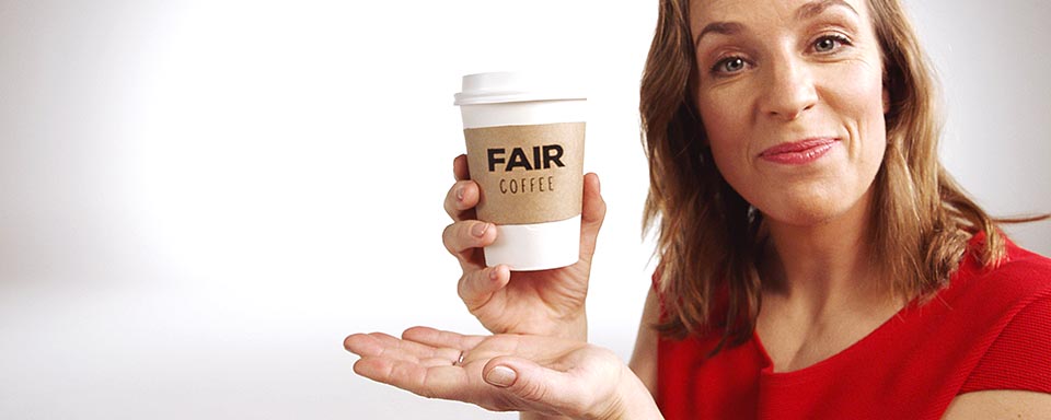 Vrouw in het rood gekleed houdt een beker koffie met de letters fairtrade omhoog | a.s.r.