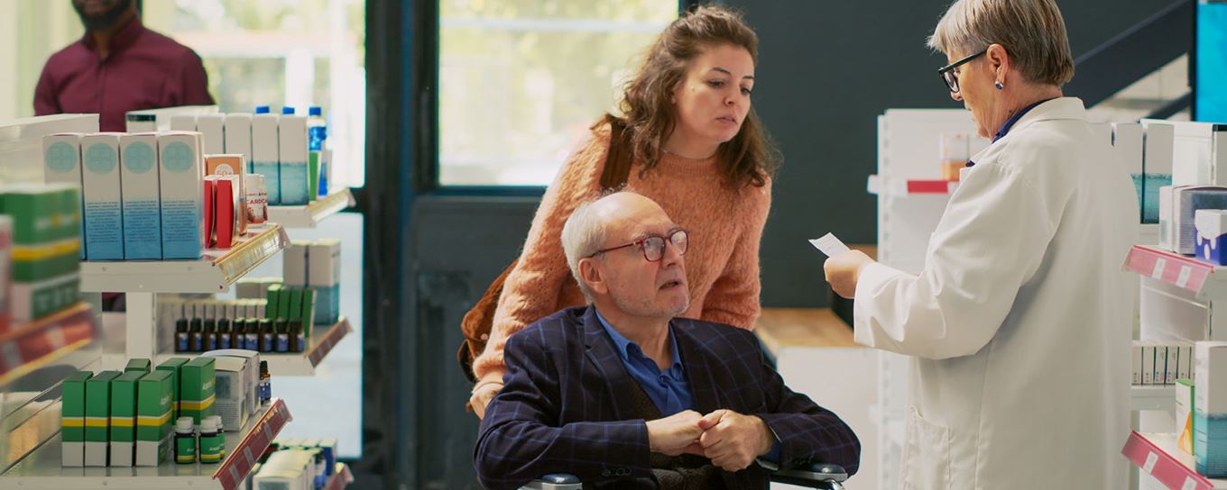 Vrouw en oudere man in rolstoel bij de apotheek