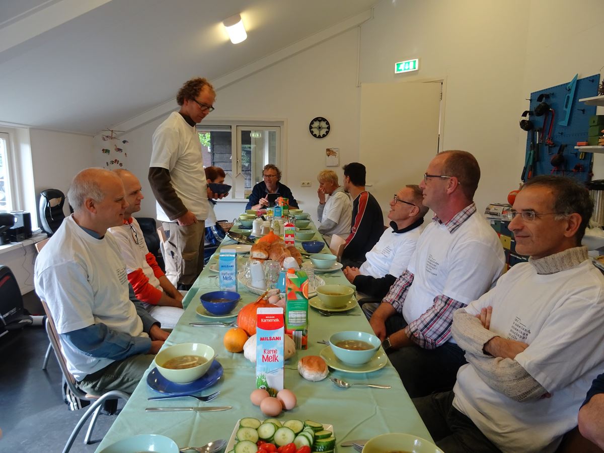  a.s.r. vrijwilligers eten samen aan een lange tafel