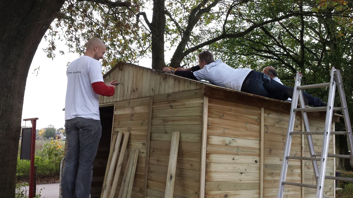a.s.r. vrijwilligers bouwen een houten schuurtje