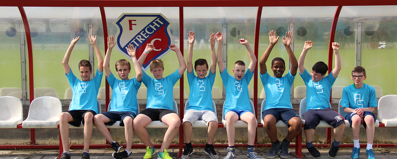 Kinderen juichen in de dug-out tijdens een FC Utrecht voetbalclinic