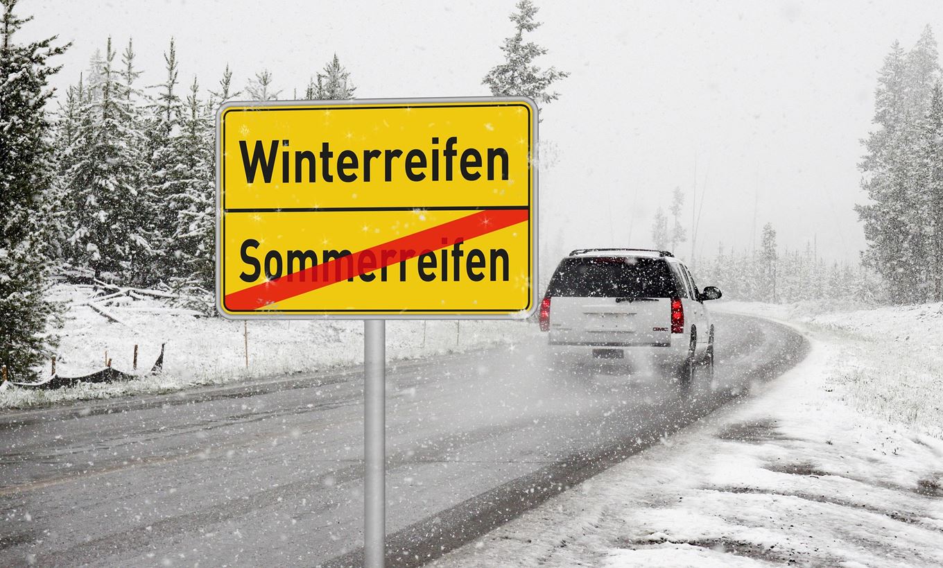 verkeersbord winterbanden met auto die voorbij rijdt