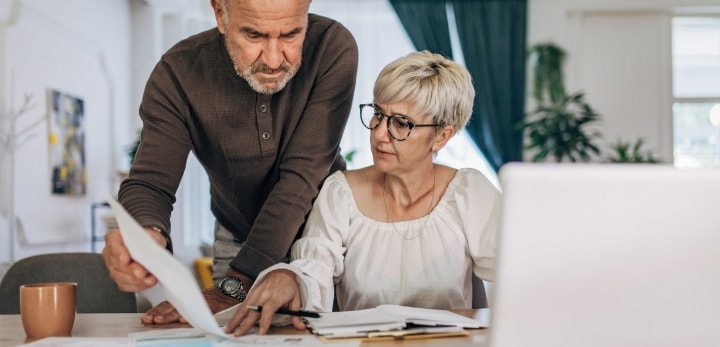 Afbeelding van een bejaarde man en vrouw achter een computer administratie aan het regelen