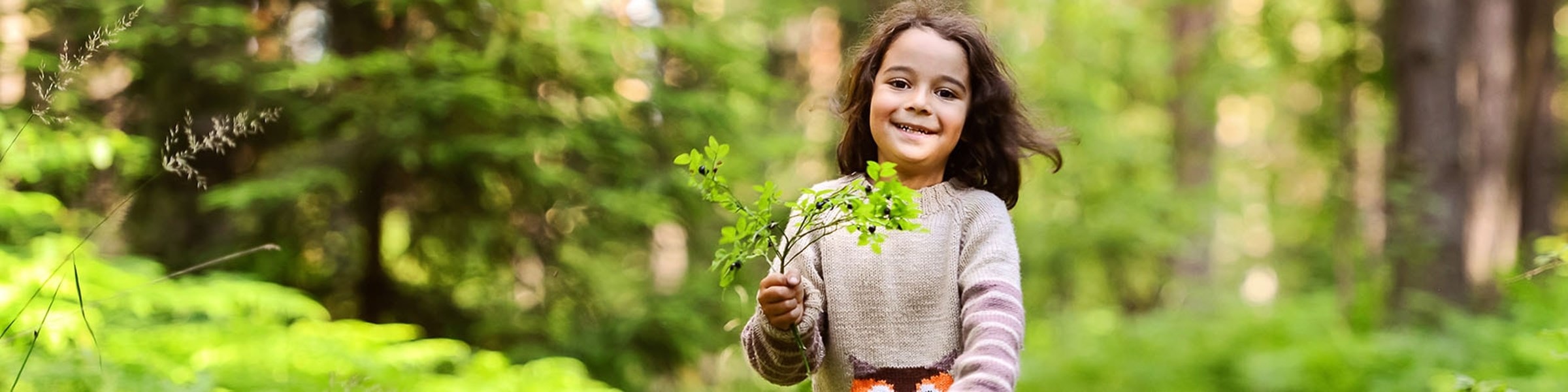 Afbeelding van een meisje in het bos met een geplukte takjes in haar handen