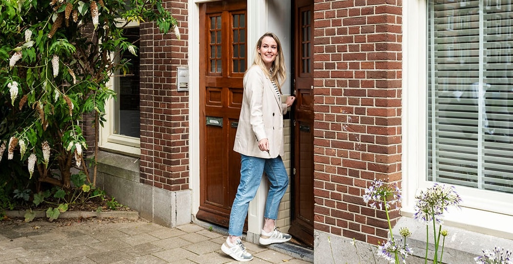 Vrouw opent de deur van een huis en stapt naar binnen.