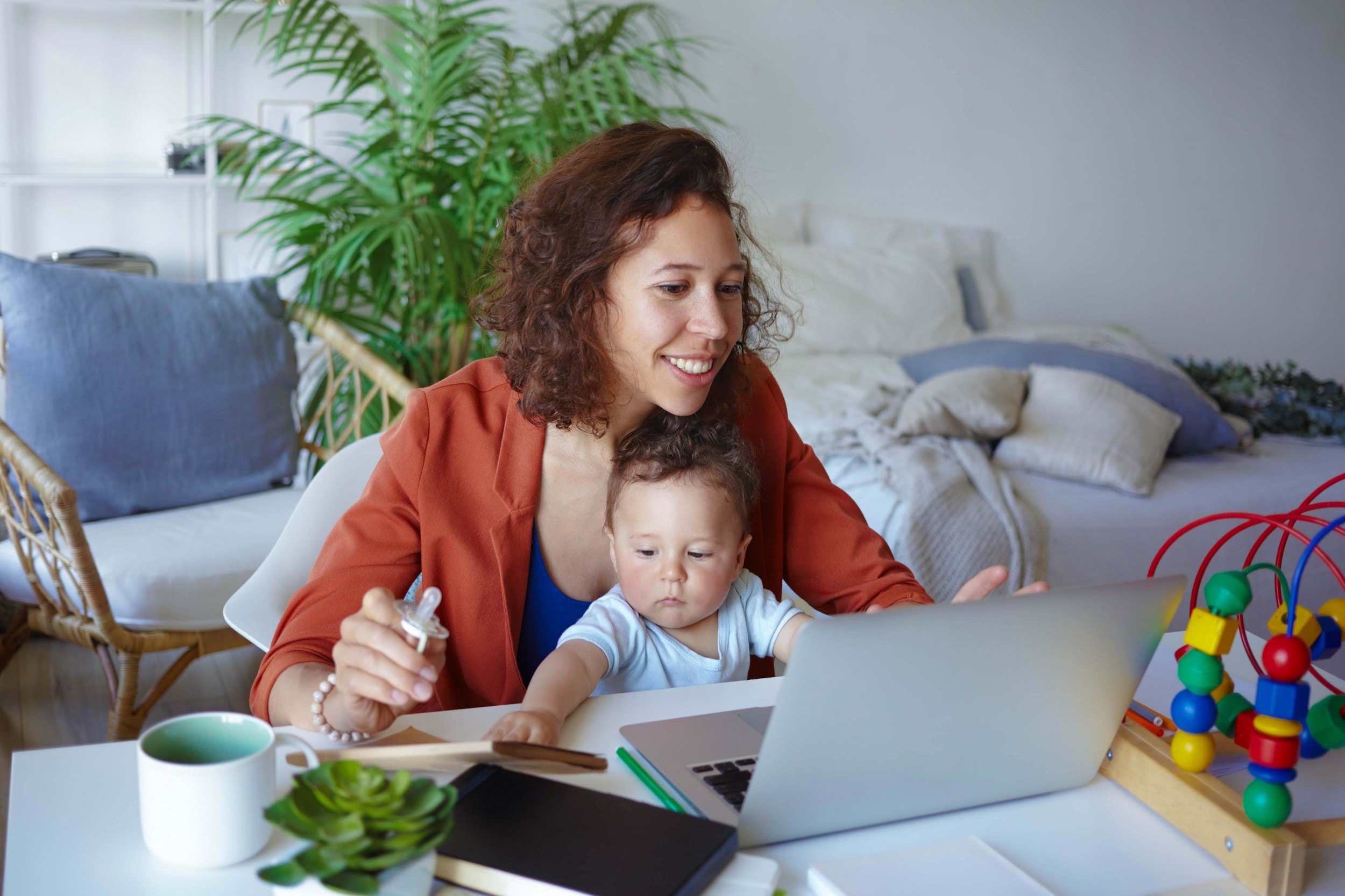 Vrouw met baby op schoot doet een financiele check bij Ik Denk Vooruit op haar laptop