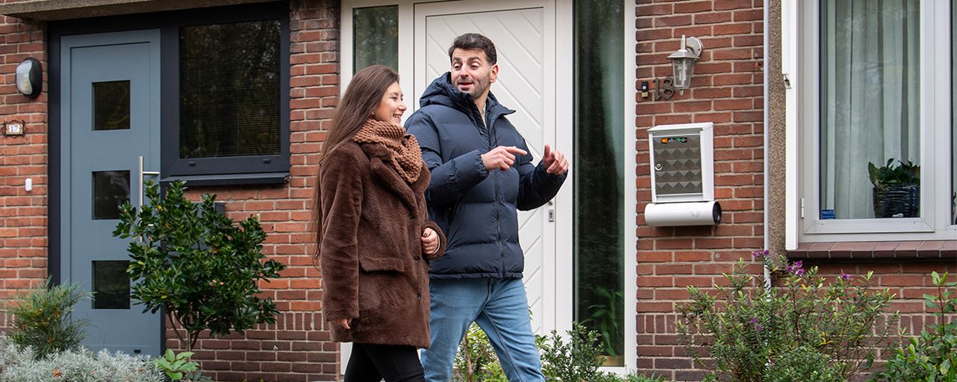 Een jonge man en jonge vrouw wandelend door een straat met rijtjeswoningen