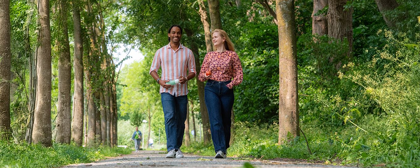 jonge man en jonge vrouw wandelen samen gezellig door het bos