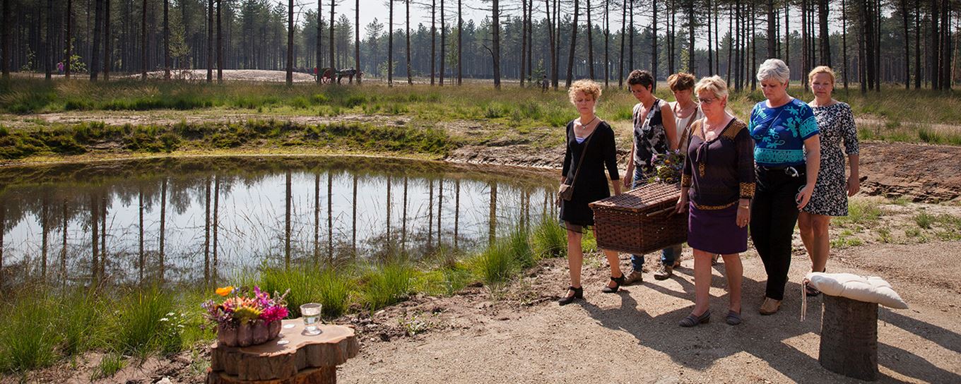 6 vrouwen tillen een begraafkist in de natuur