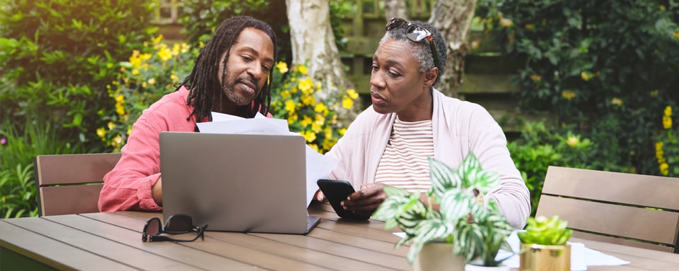 Koppel zit aan tuintafel met laptop