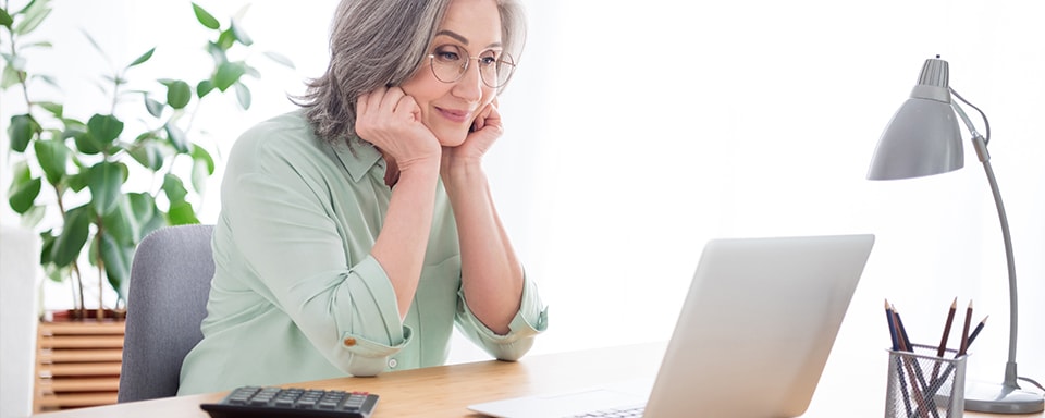 Senior vrouw kijkt aandachtig naar laptop