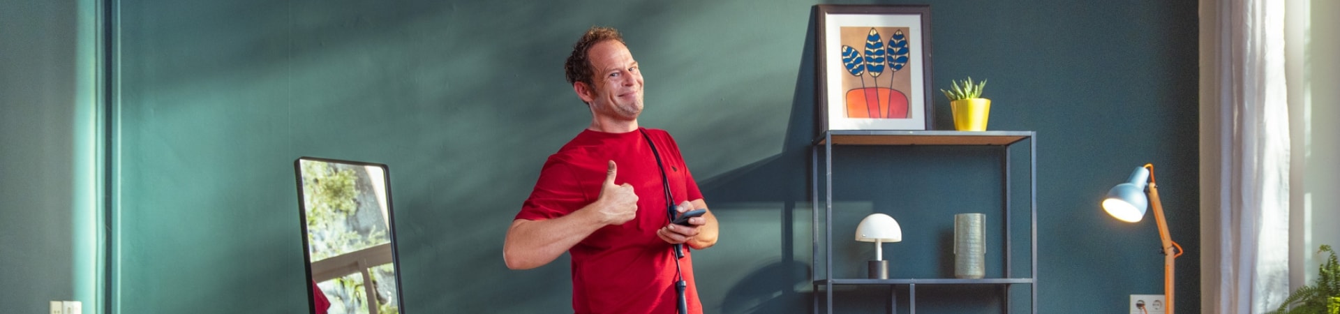 man in sportkleding staat in zijn woonkamer en steekt zijn duim lachend op